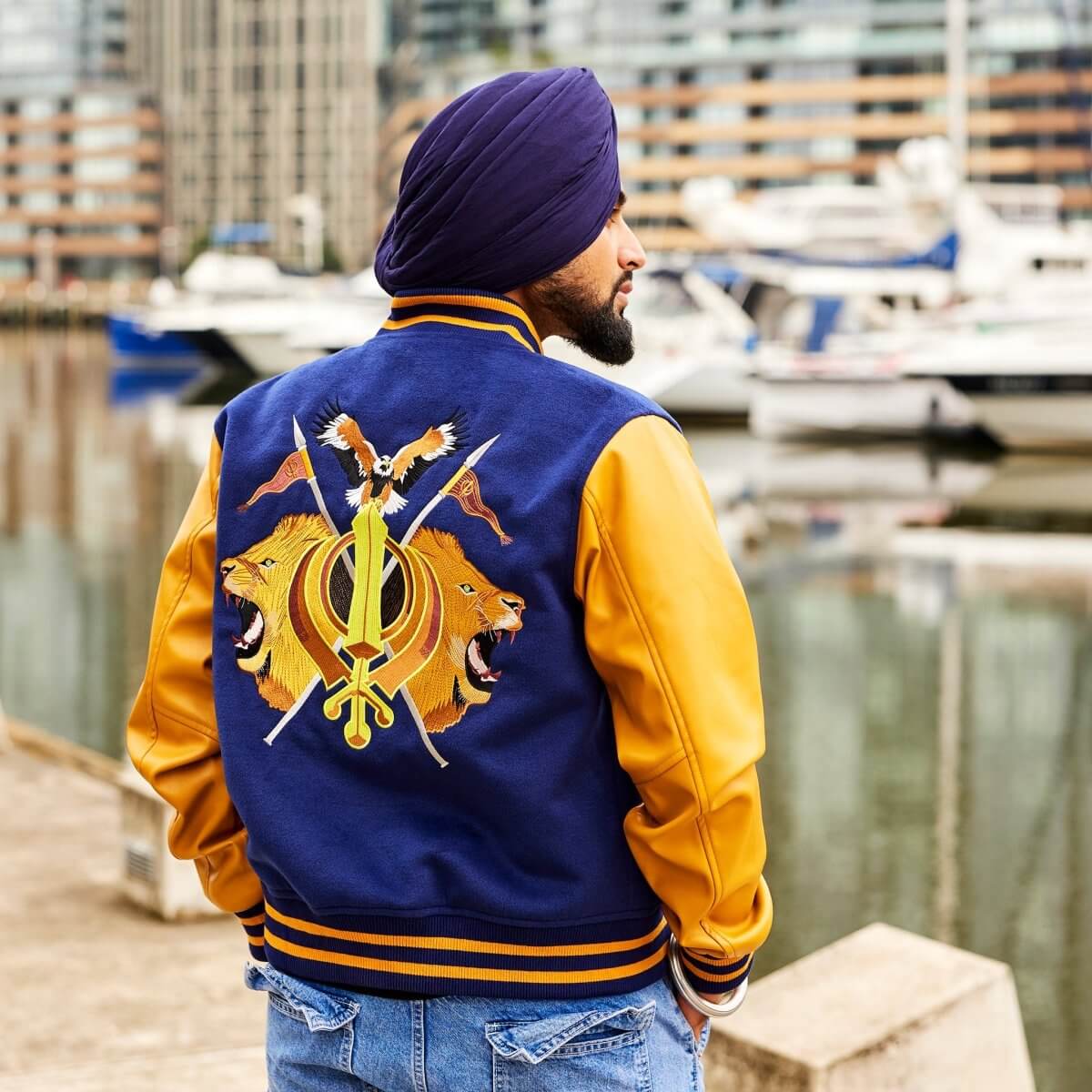 Sikh man wearing blue jacket facing the water